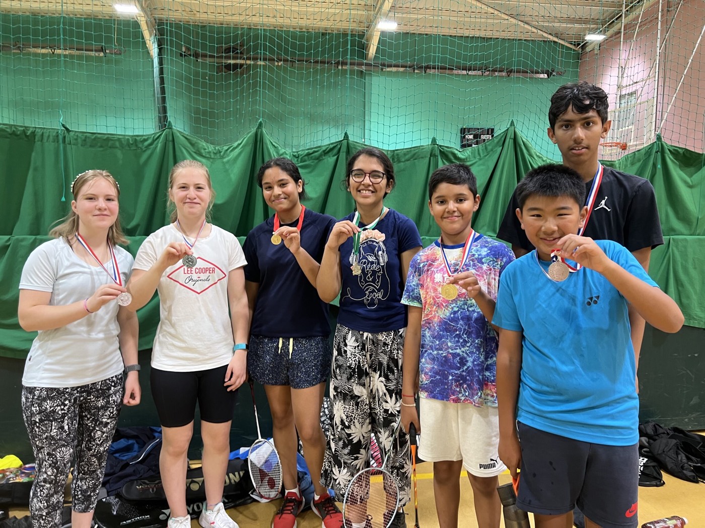 Young players showing the medals they won at a junior badminton tournament