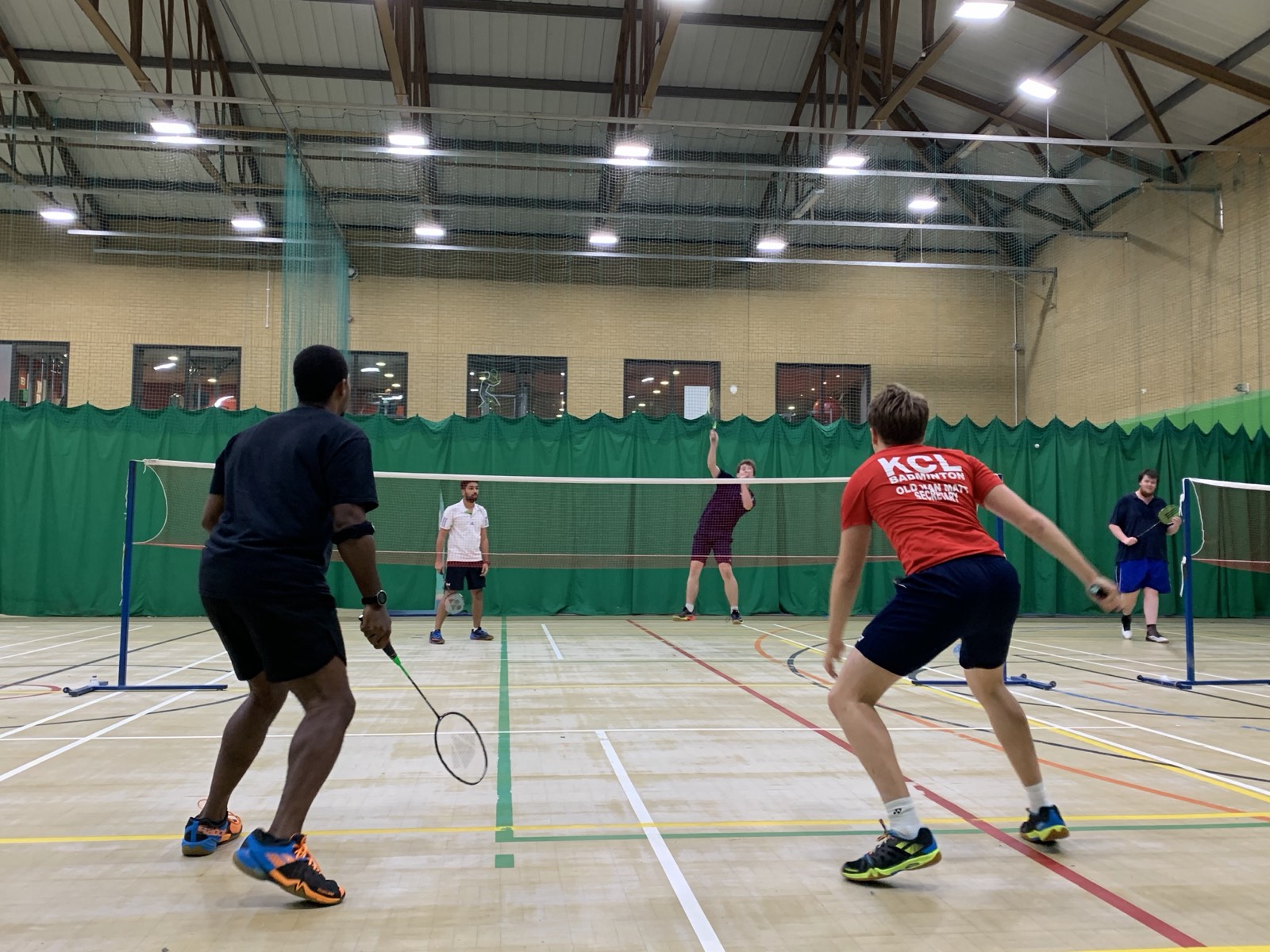 A mixed doubles rally in full swing during an adult matchplay session